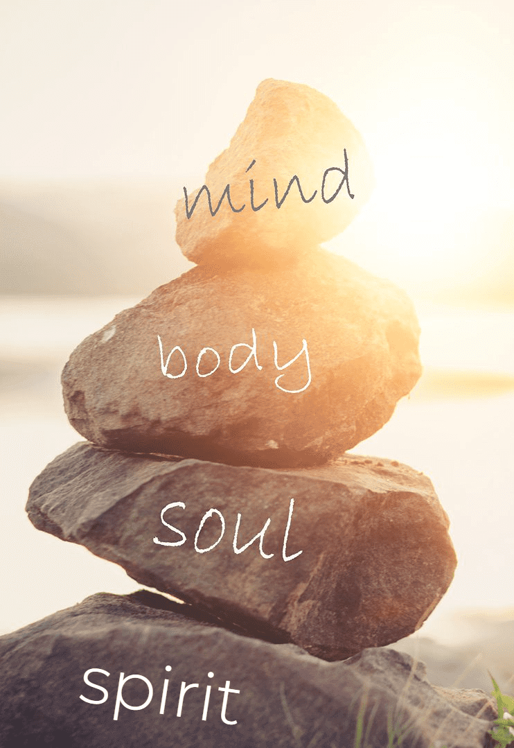 Stacked stones labeled mind, body, and soul with sunlight background.
