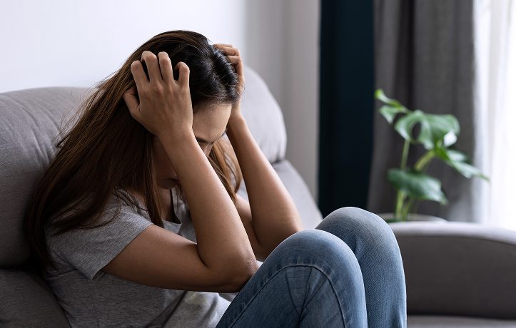 A woman sitting with her head in her hands, appearing distressed.
